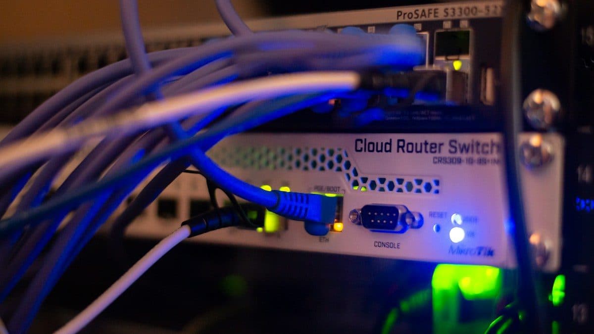 Cavi di rete blu collegati a uno switch in un armadio server, con luci accese