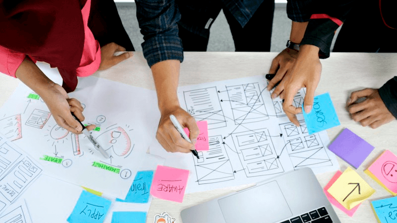 Team al lavoro su wireframe e post-it per progettare le pagine di un sito web