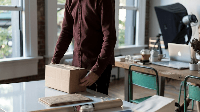 Pacco di un e-commerce pronto per la spedizione su sfondo scuro con luce digitale arancione