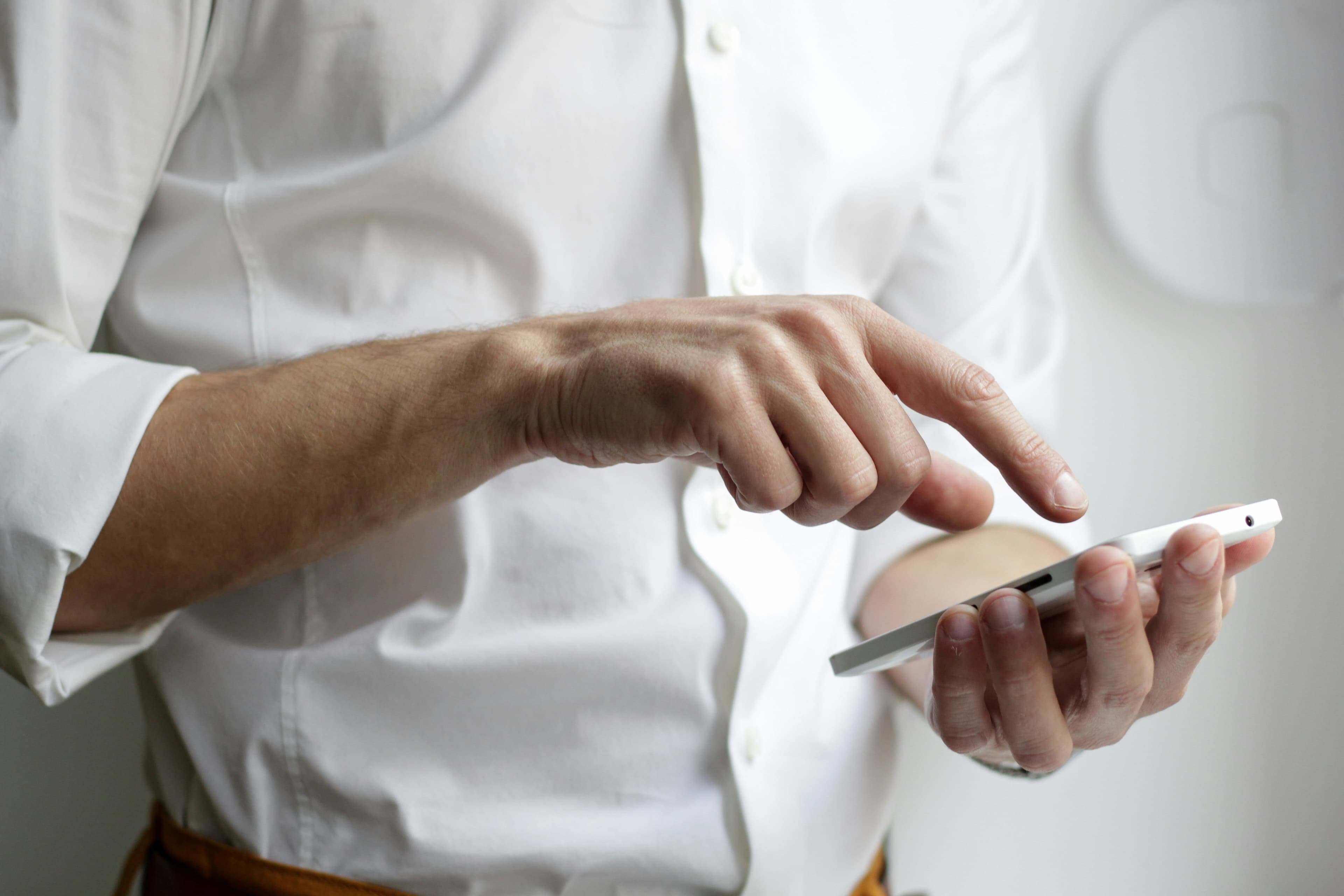 Persona che tiene in mano uno smartphone Android bianco, rappresentazione dello sviluppo app mobile