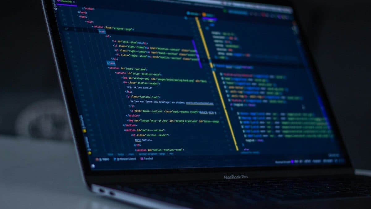 Portatile aperto in penombra su un editor di codice con righe di HTML colorate